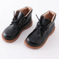 A pair of black faux leather booties with lace-up fronts and brown soles.