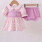 Baby girl's outfit with polka dot dress and pink bloomers on a hanger against a white background