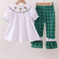 White top with embroidered details and green plaid pants on hangers against a white background
