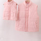 Two pink puffer vests hanging on a rack against a white background