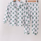 Children's pajama set with tree pattern on hangers against a white background